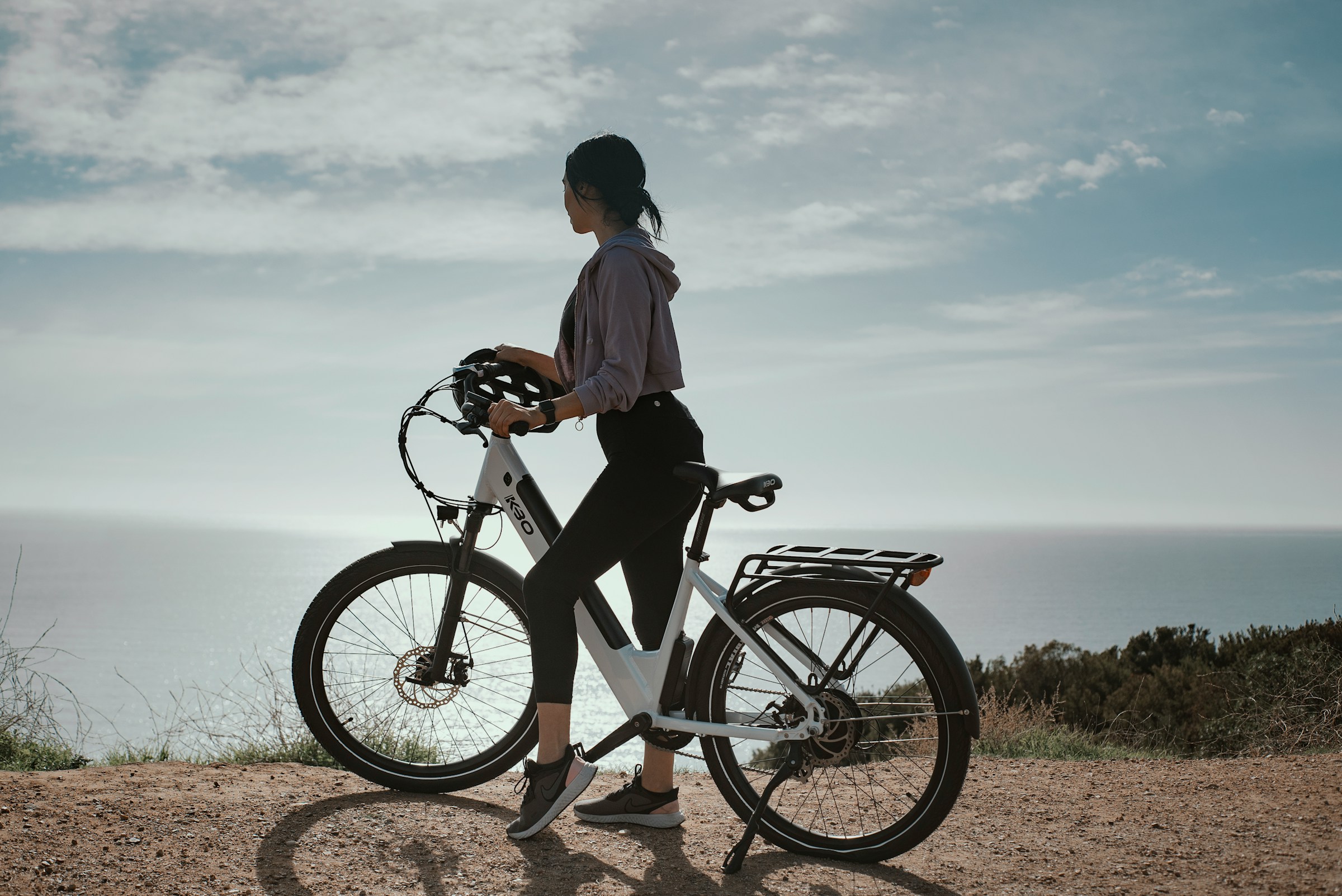 Woman on bike looking out over the coast and sea in Mallorca
