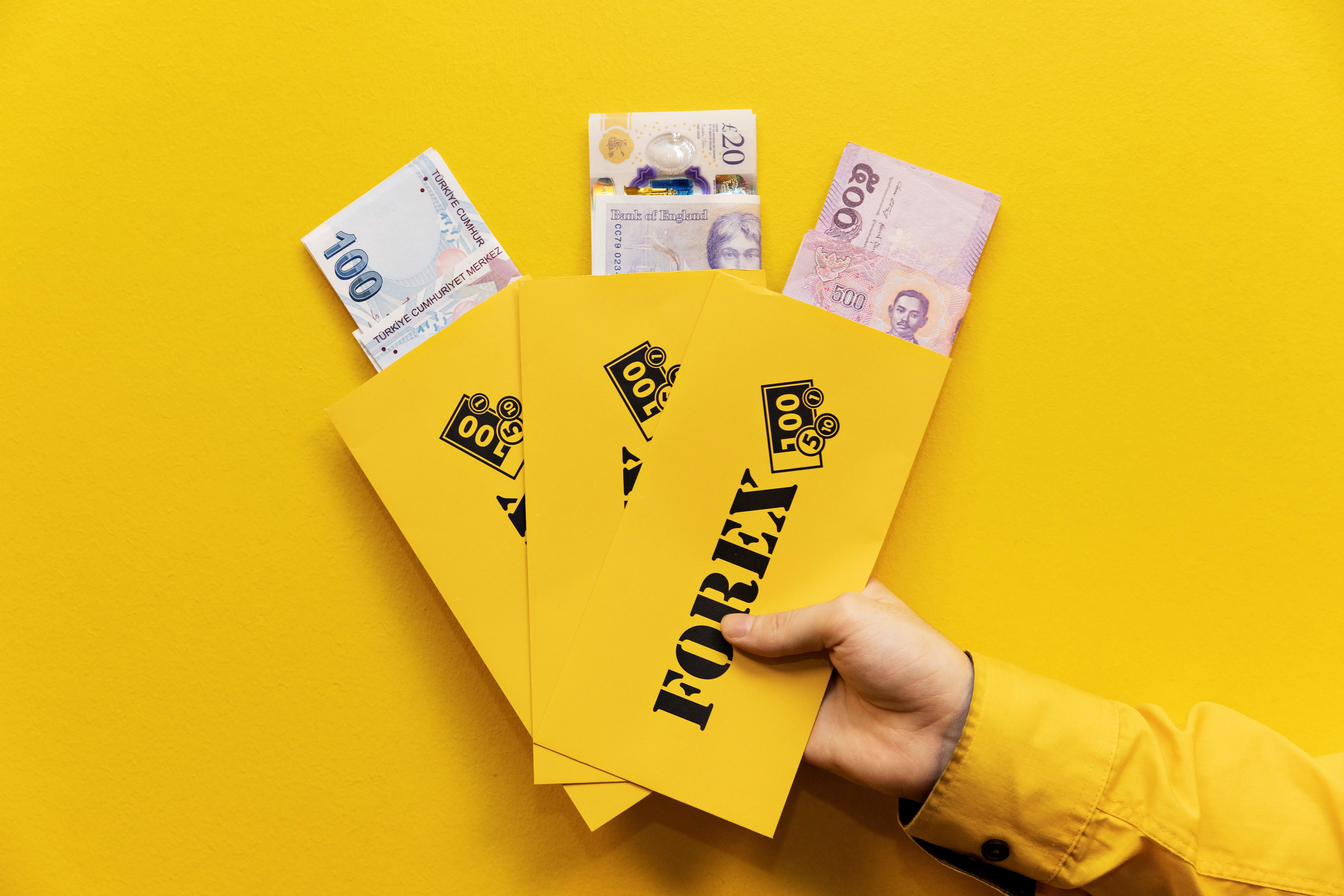 FOREX currency envelopes are held by a hand with travel currency visible in them