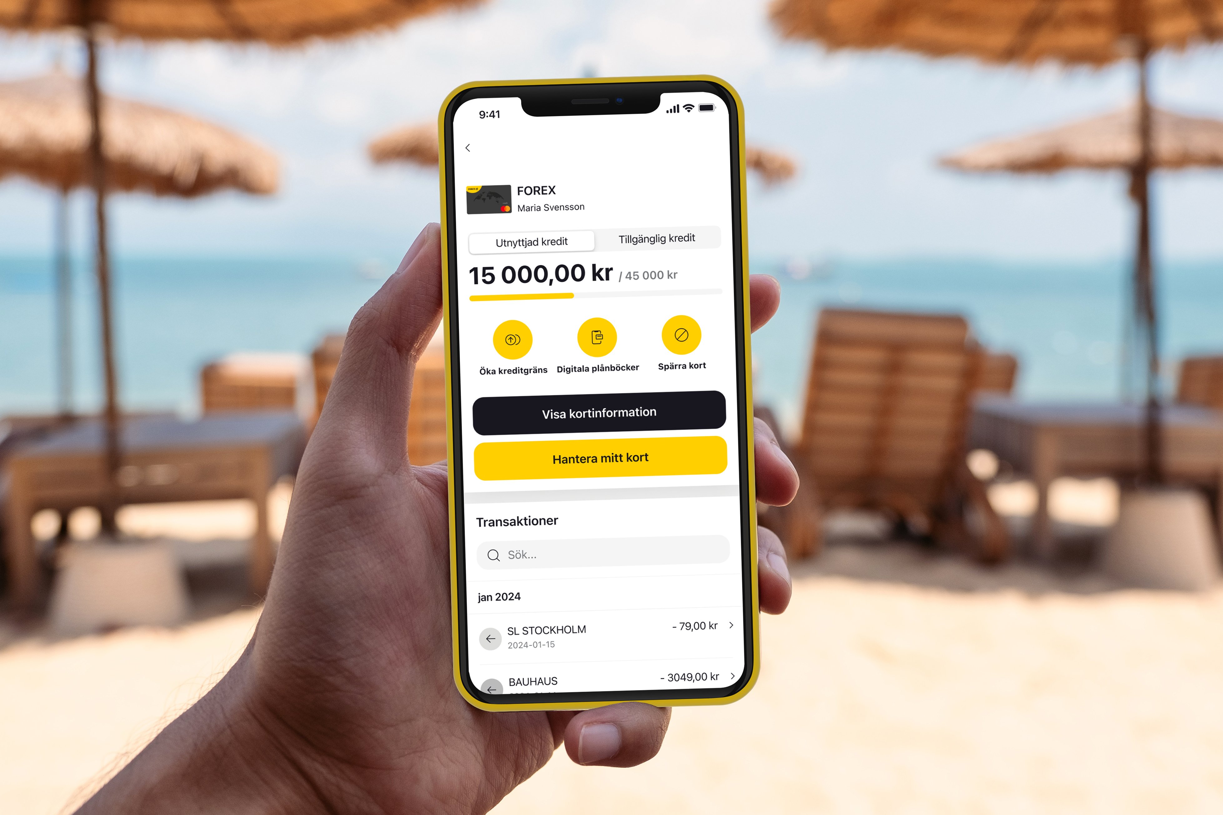Person holding a smartphone on a beach showing an app from FOREX with credit card details and transaction history, against a backdrop of sun loungers and umbrellas by the sea.