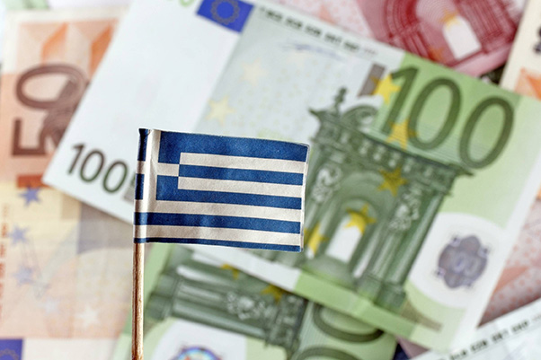 Greek flag in front of a pile of euro banknotes of different denominations.