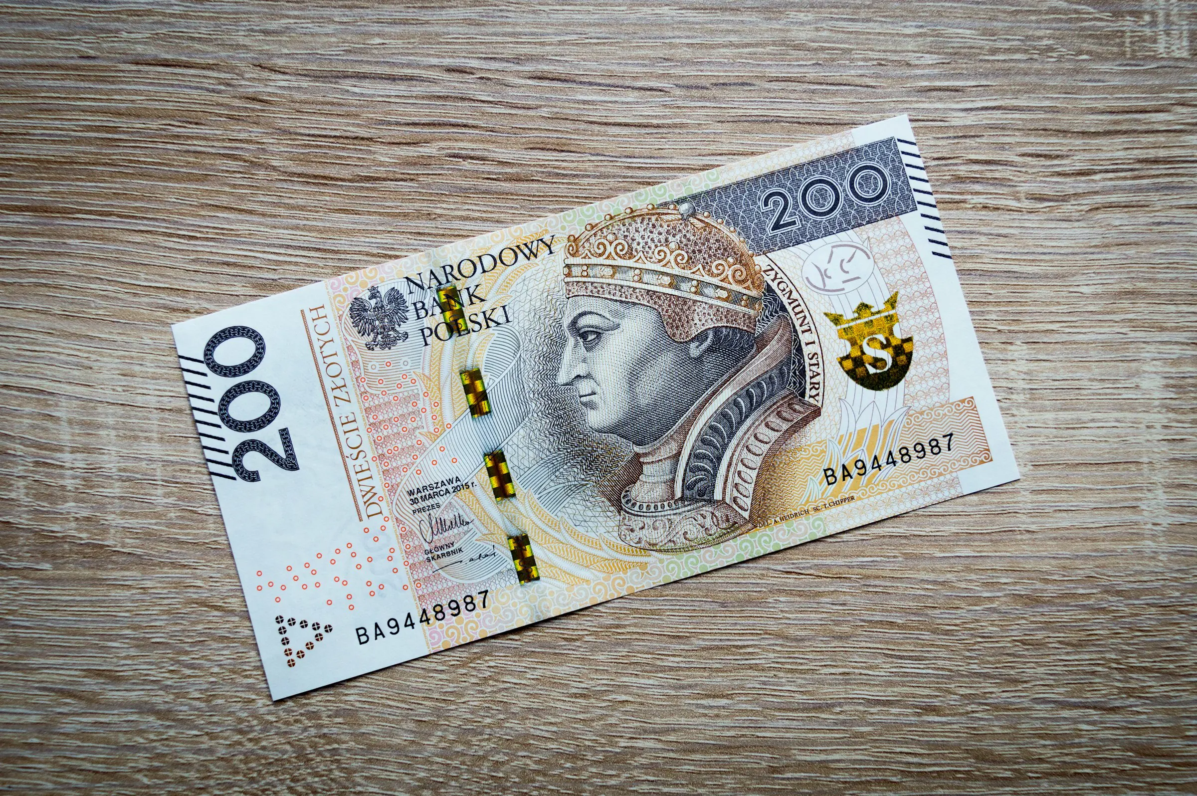 Polsk 200 zlotysedel på en trämönstrad bakgrund.