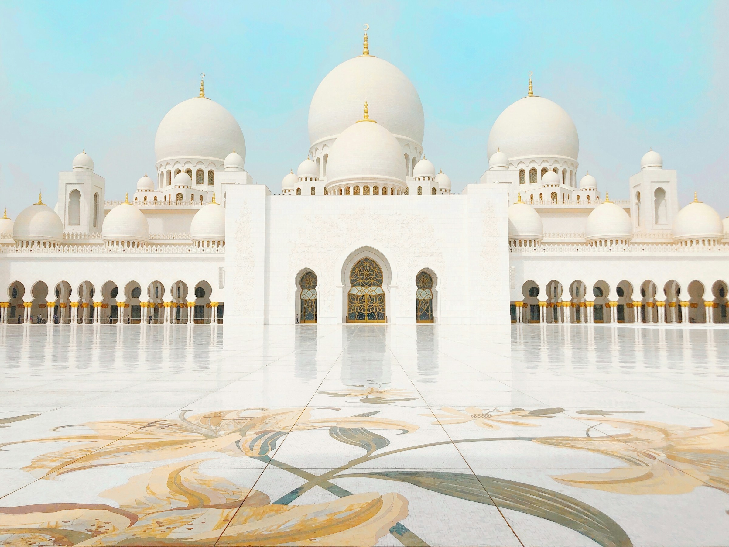 Sheikh Zayed Grand Mosque with intricate marble courtyard, Abu Dhabi, UAE, under a clear blue sky.