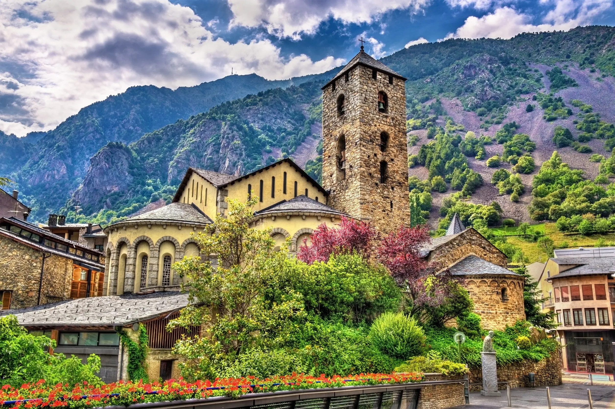 Stenkyrka i Andorra med grönskande berg i bakgrunden under molnig himmel
