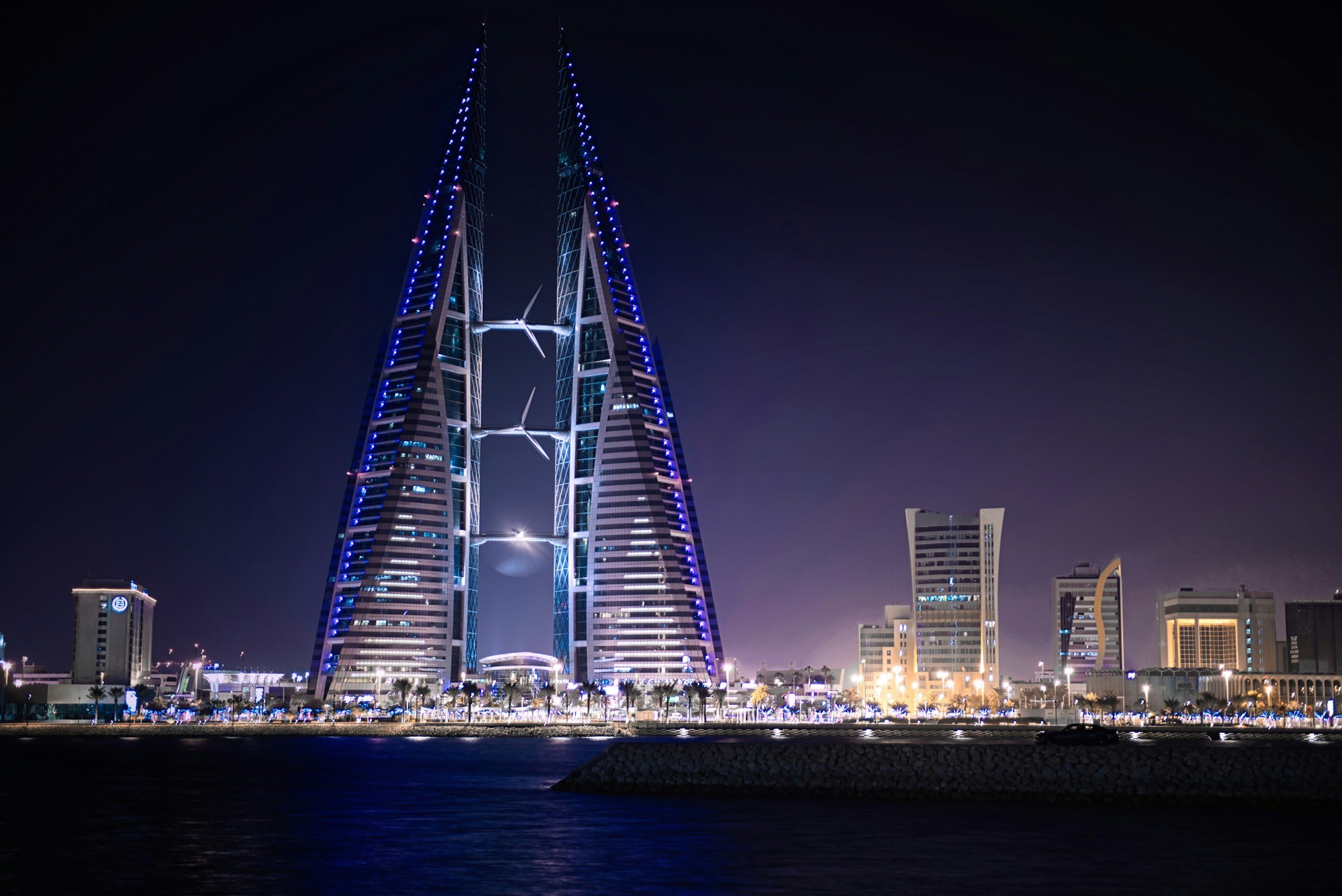 Bahrain World Trade Center illuminated at night with surrounding cityscape.