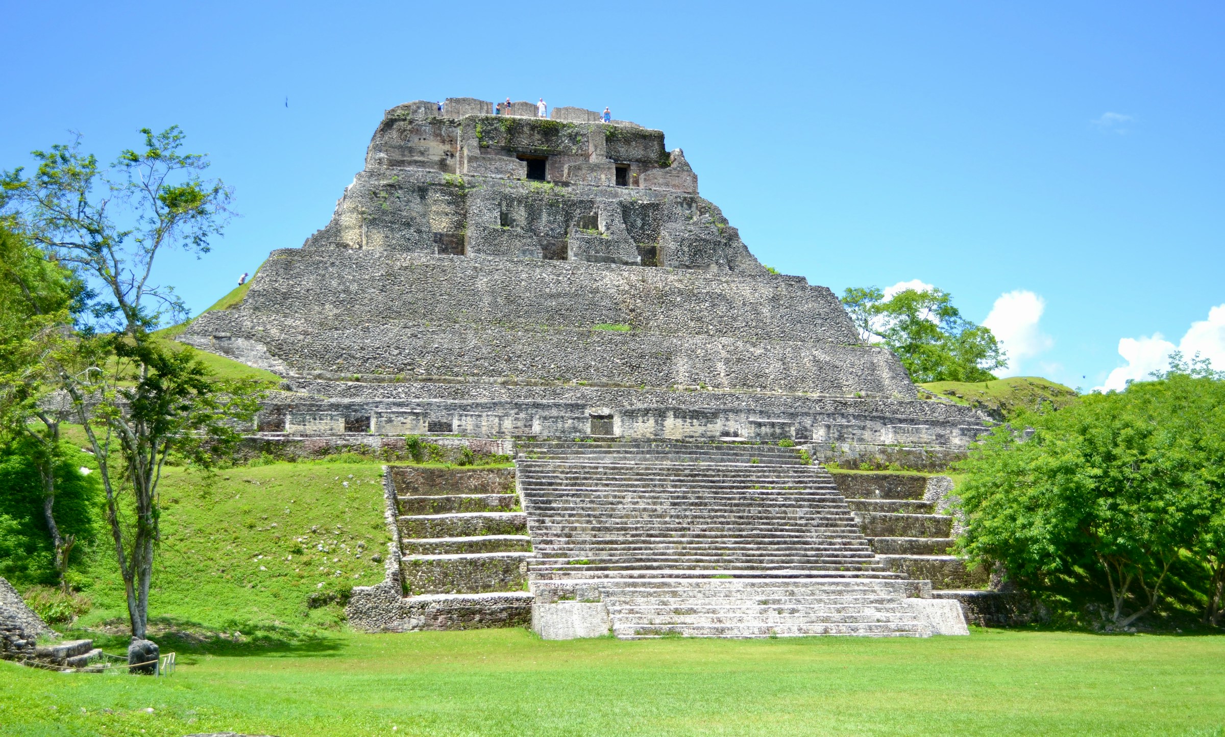 Ancient Mayan pyramid of Xunantunich in Belize, surrounded by lush greenery and under a clear blue sky.