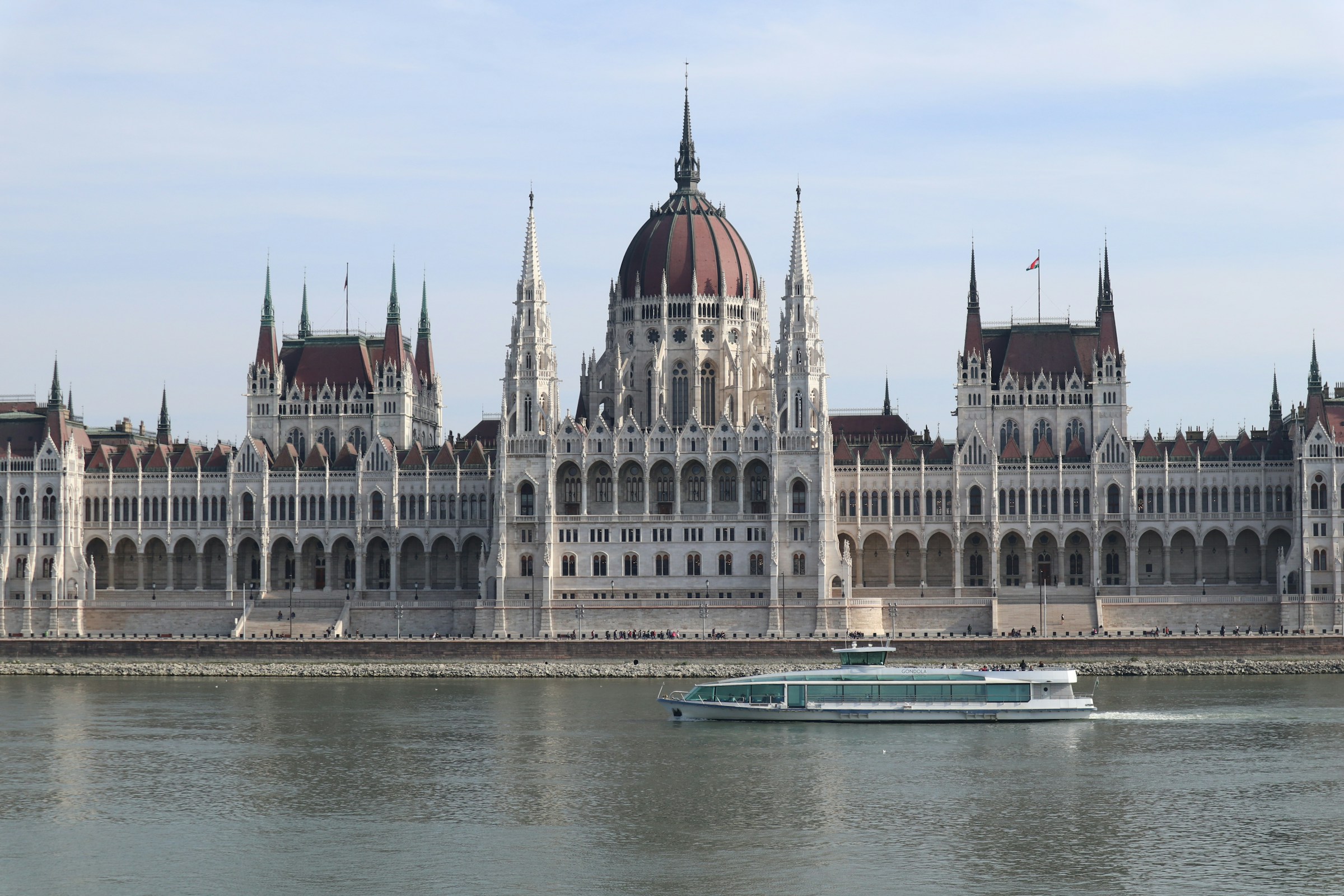 Hungarian Parliament Building along the Danube River with a passing tour boat in Budapest, Hungary.