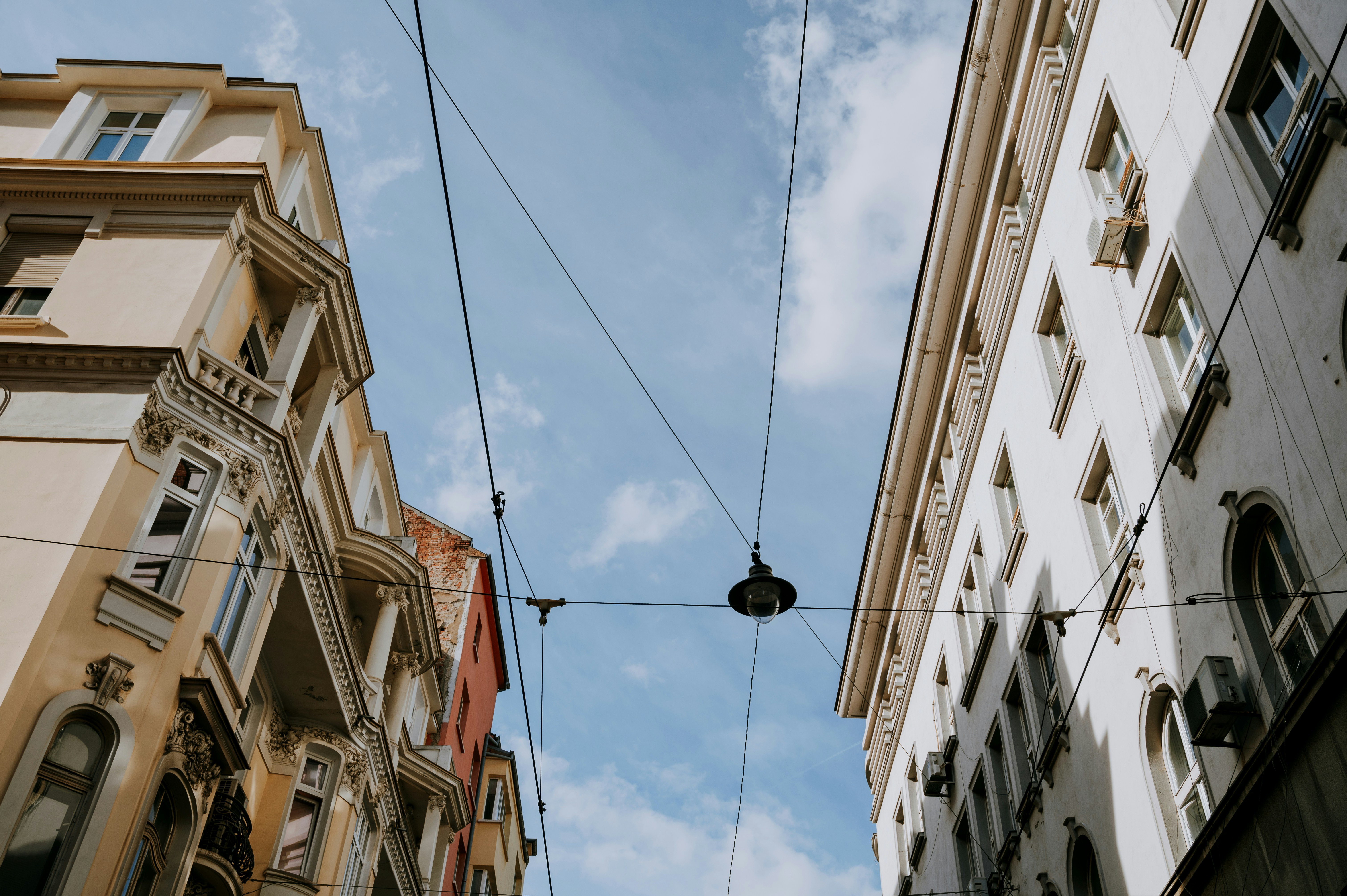 Kaksi vanhaa rakennusta sinisen taivaan alla, joissa koristeellisia yksityiskohtia ja ikkunalautoja