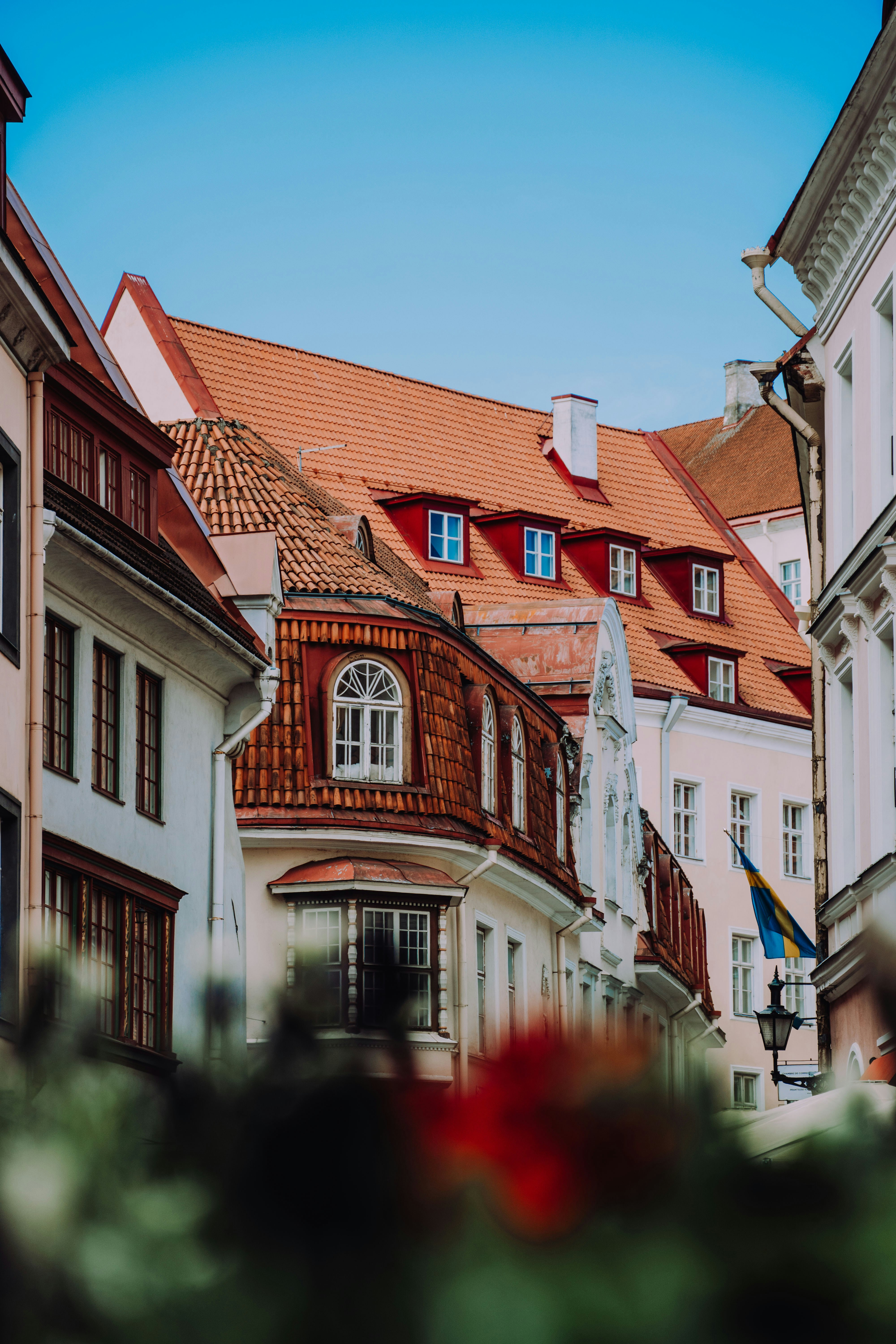 Gamla byggnader med röda tegeltak i en historisk europeisk stad på en solig dag, med klar blå himmel i bakgrunden