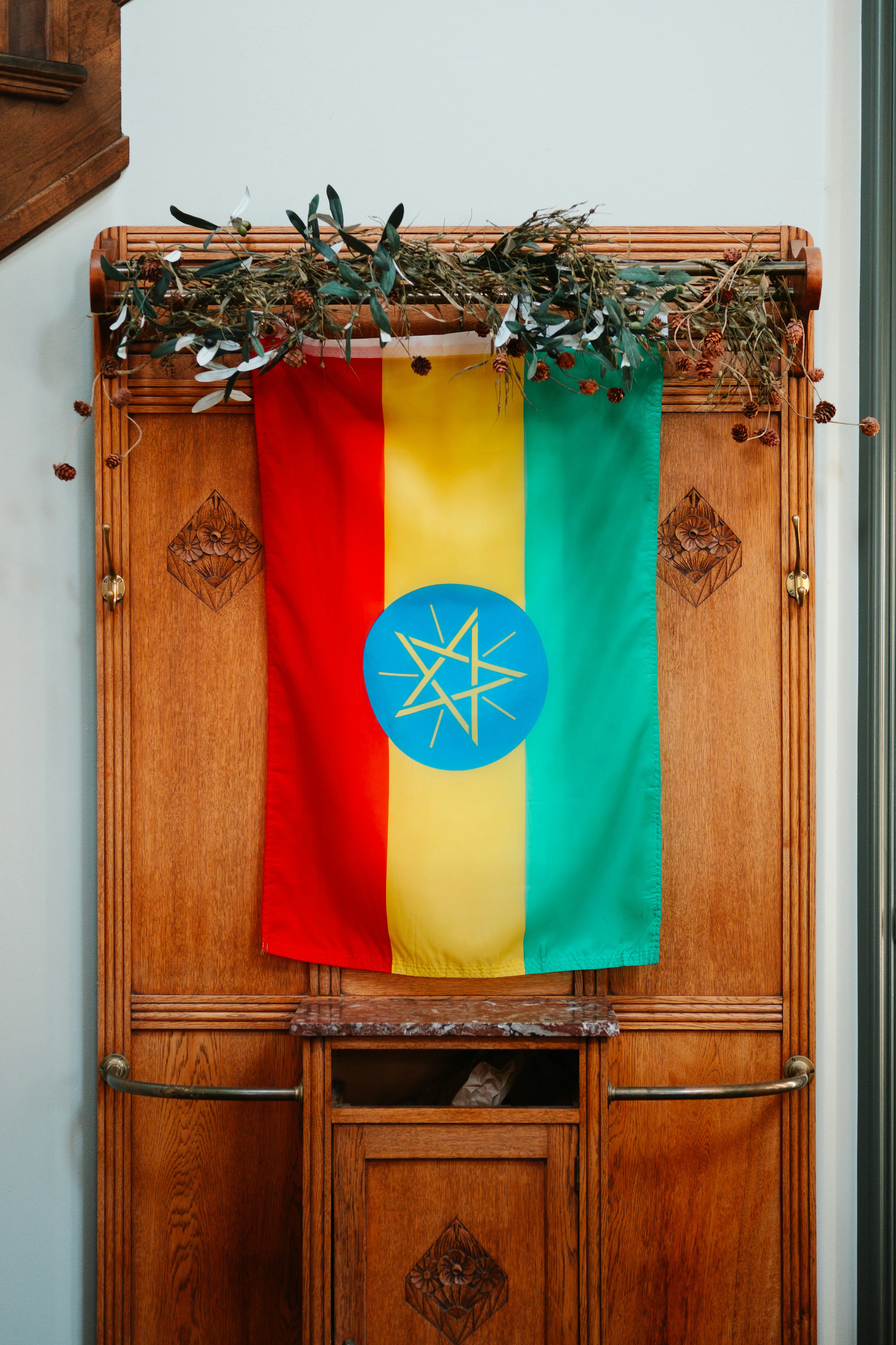 Etiopisk flagga hänger på en trävägg med dekorativa kvistar ovanpå