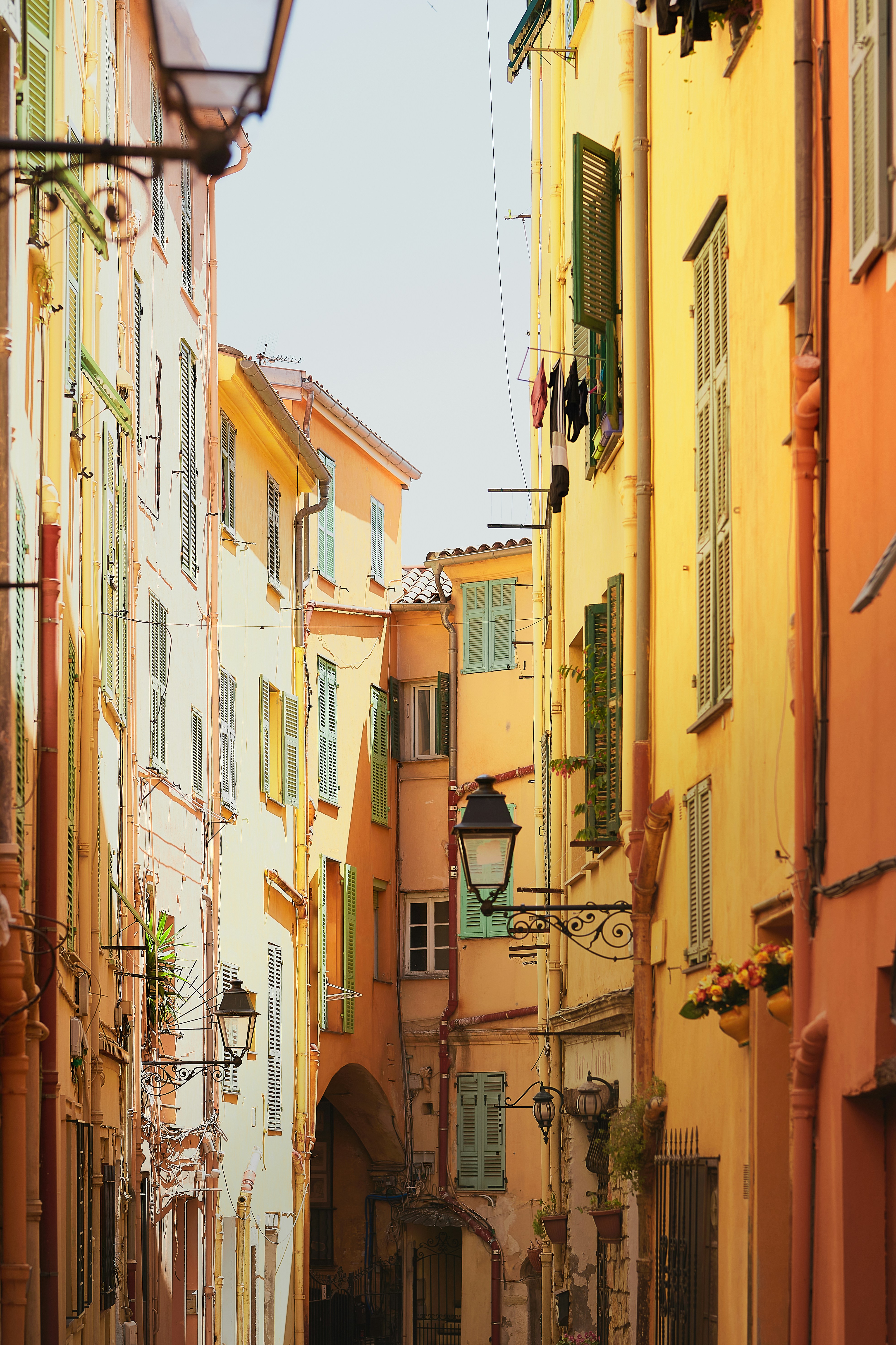 Smala, färgglada gränder i en pittoresk europeisk stad med ljusgula och orange byggnader och fönsterluckor