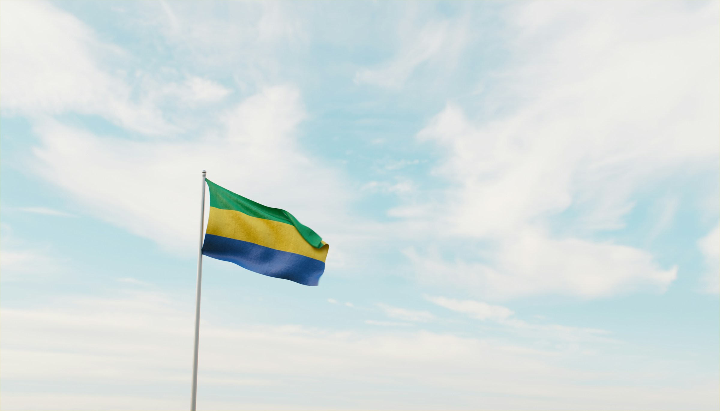 Gabon flag waving against a cloudy blue sky background.