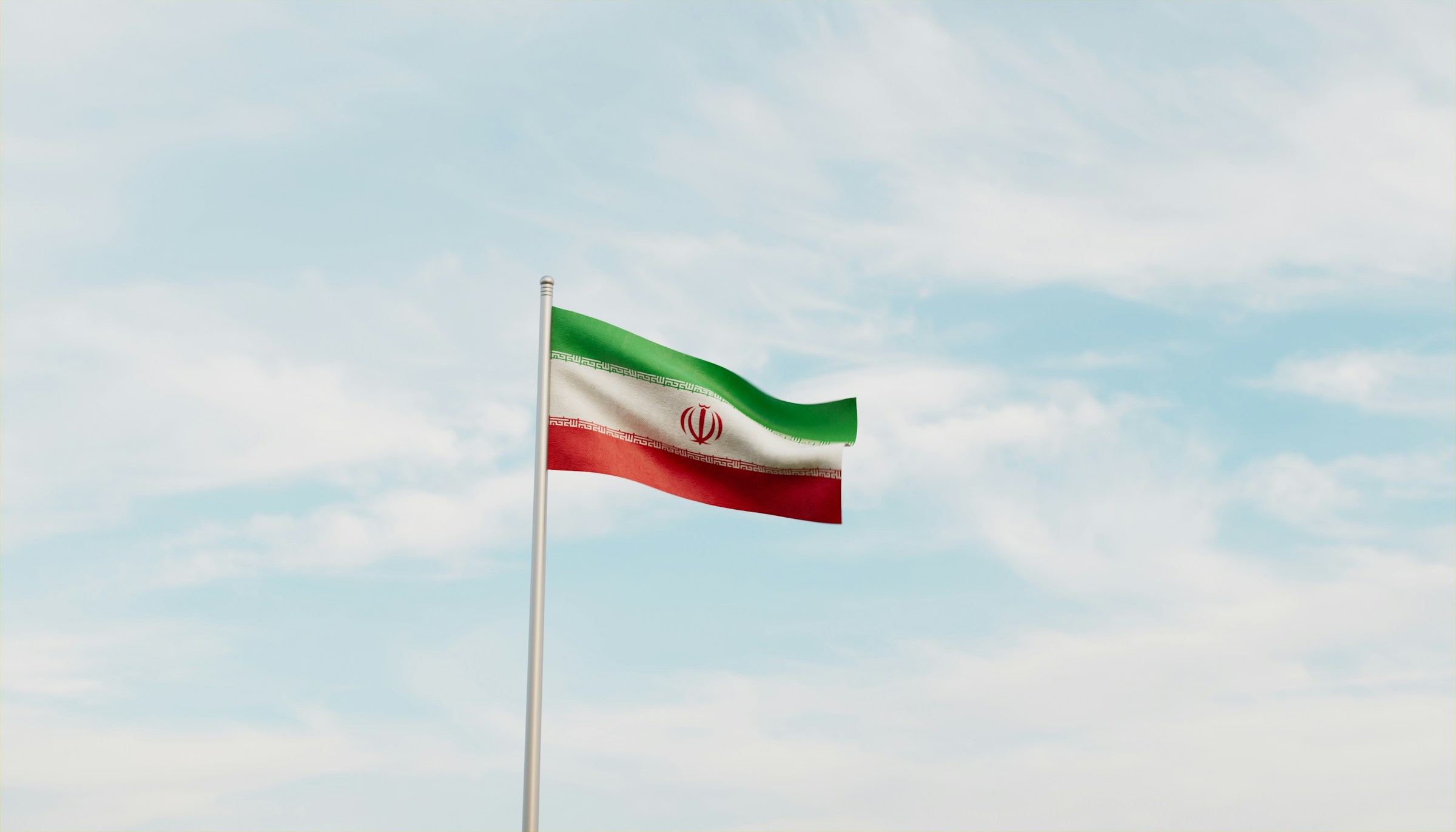 Iranian flag waving against a clear blue sky.