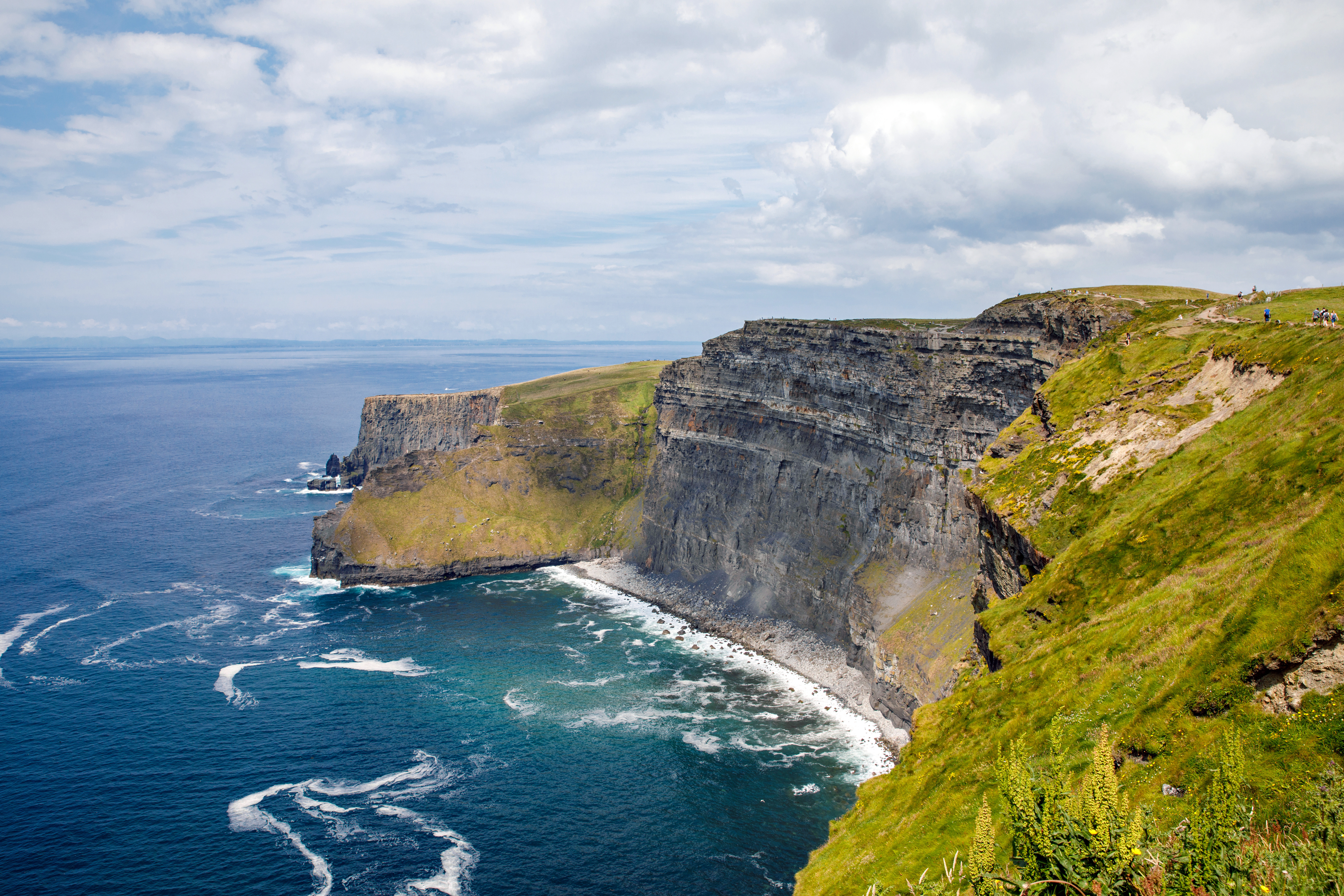 Irlannin Cliffs of Moher, jylhät kallioseinämät Atlantin valtameren rannalla, vehreä maisema ja aallot paiskautuvat kallioihin