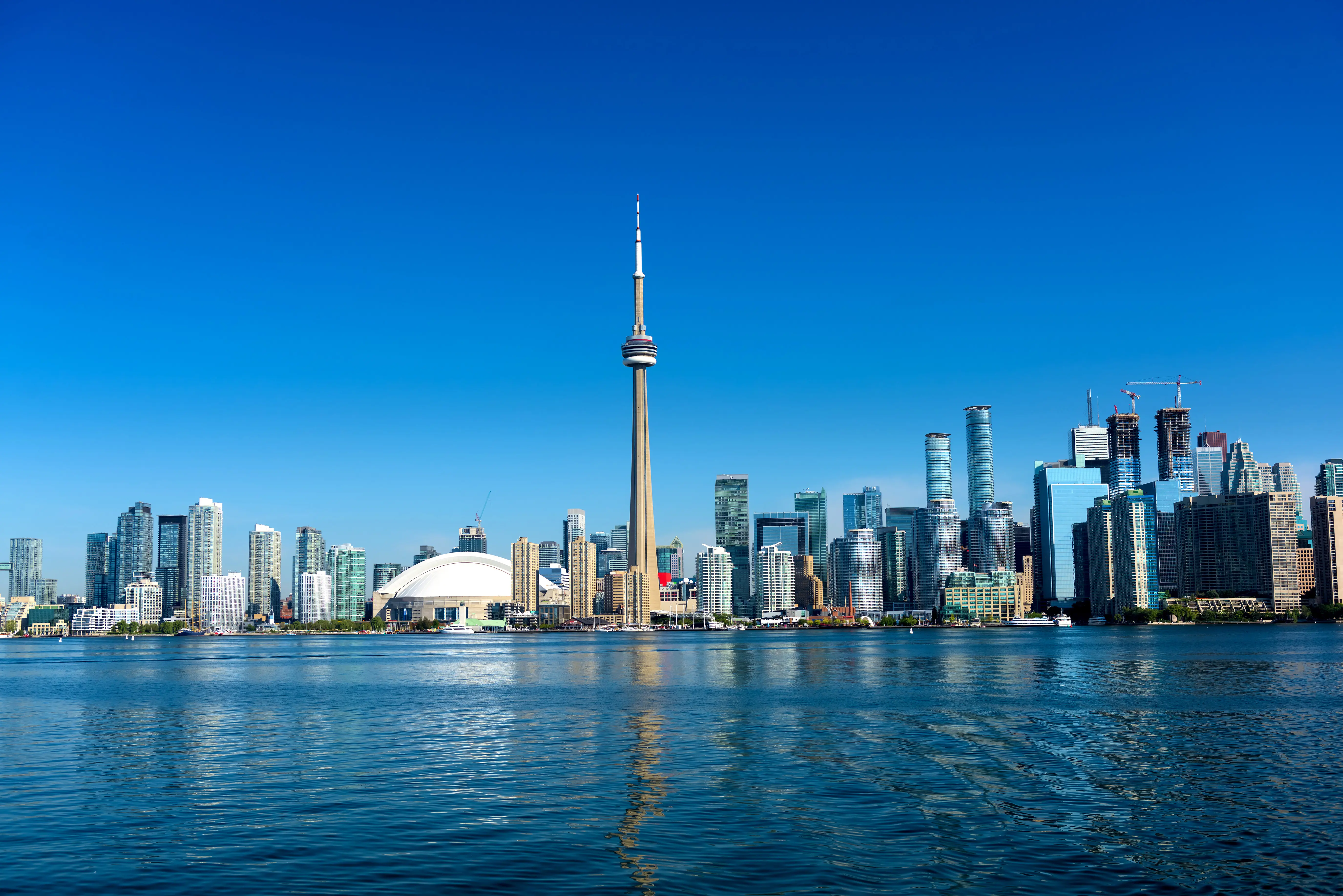 Toronton kaupunkisiluetti CN Towerin kanssa kirkkaassa päivänvalossa, etualalla Ontarionjärvi