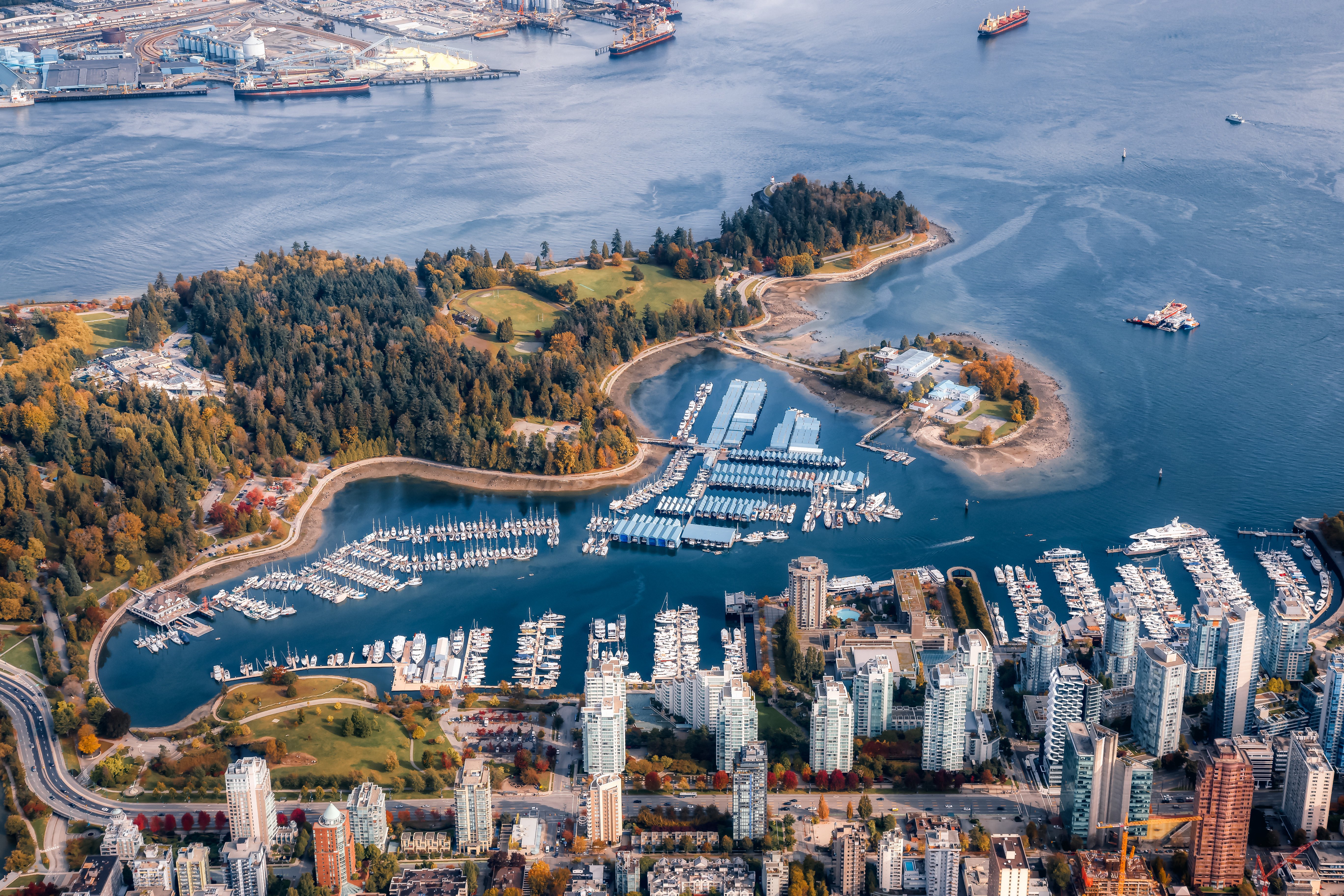 Flygbild av Stanley Park och stadsdelen Coal Harbour i Vancouver, med småbåtshamnar och skyskrapor längs vattnet
