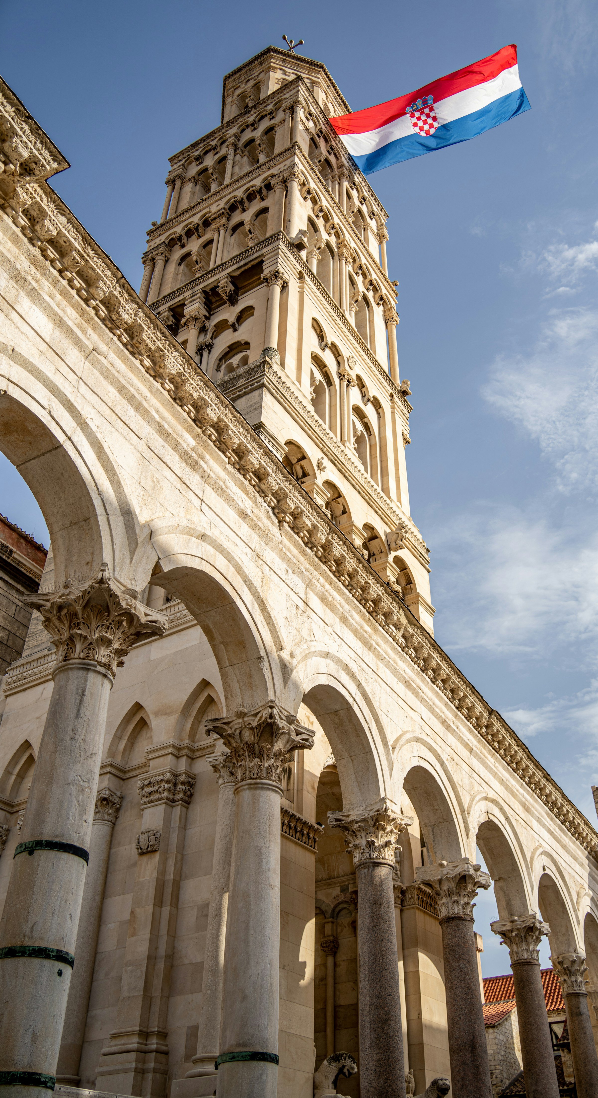 Historic bell tower of Diocletian's Palace in Split, Croatia, with Croatian flag waving against a clear sky