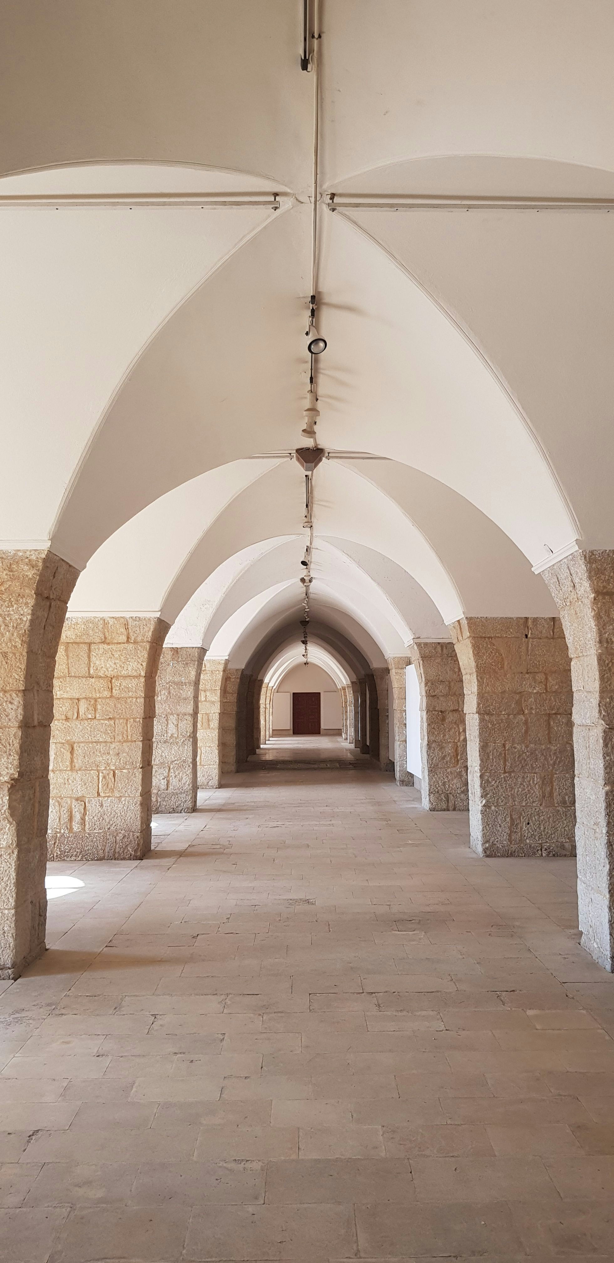 Kaareva kivikäytävä, jossa on symmetriset pylväät ja holvikatto