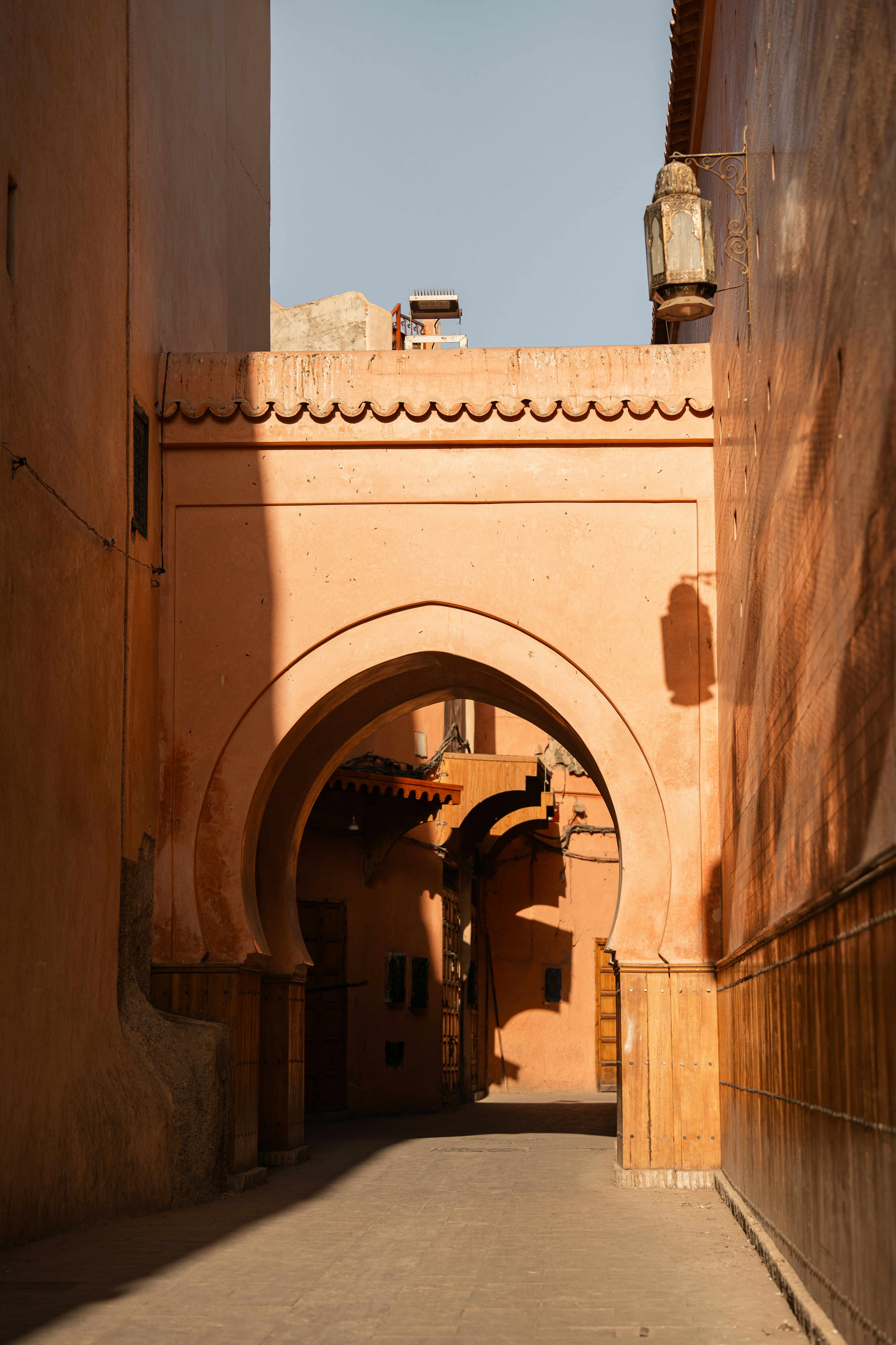 Historic archway in Marrakech's Medina, showcasing traditional Moroccan architecture with textured walls and warm, earthy tones under clear sunlight