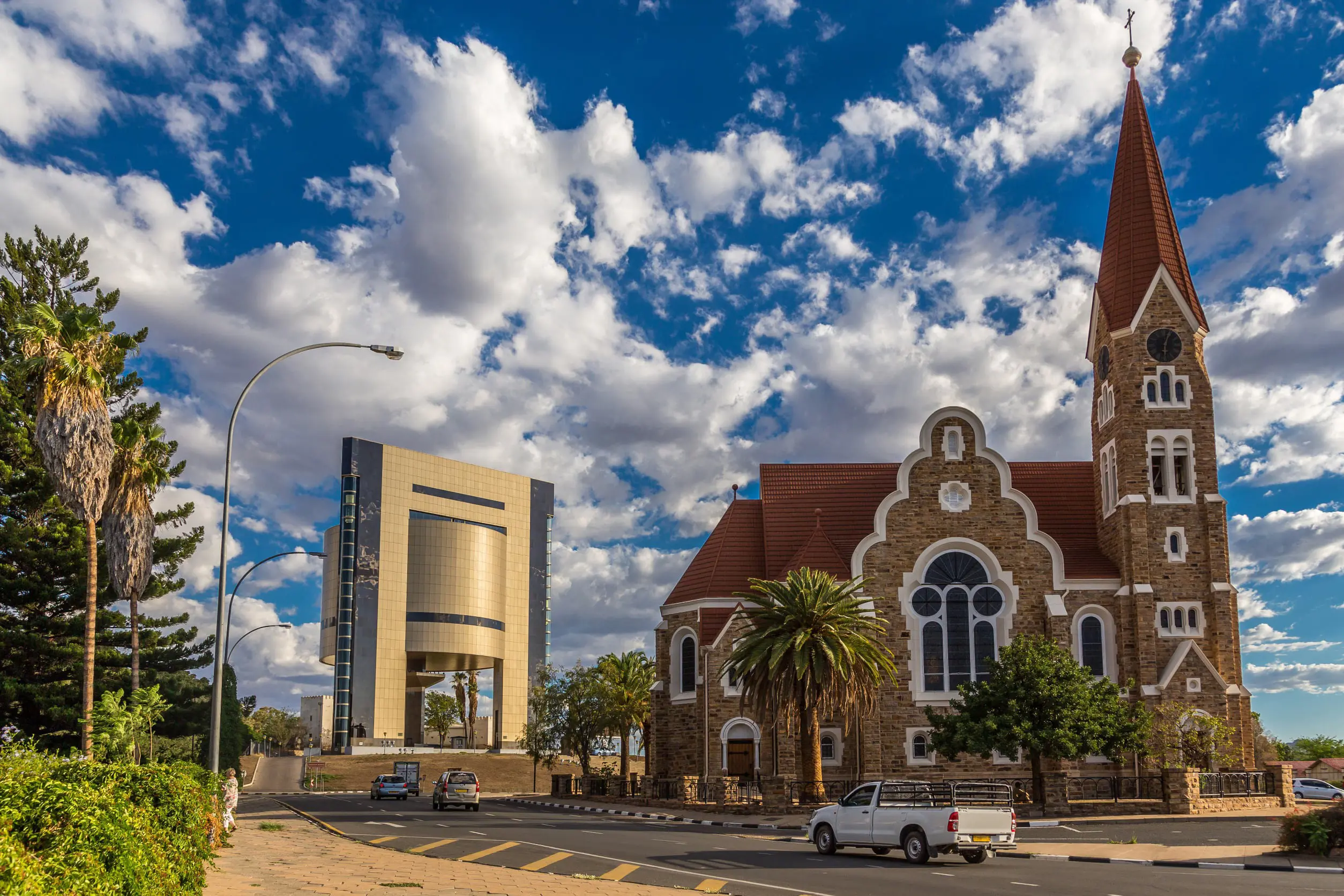 Vacker kyrka i Windhoek i tegel med grönska omkring sig och blå himmel med moln i bakgrunden