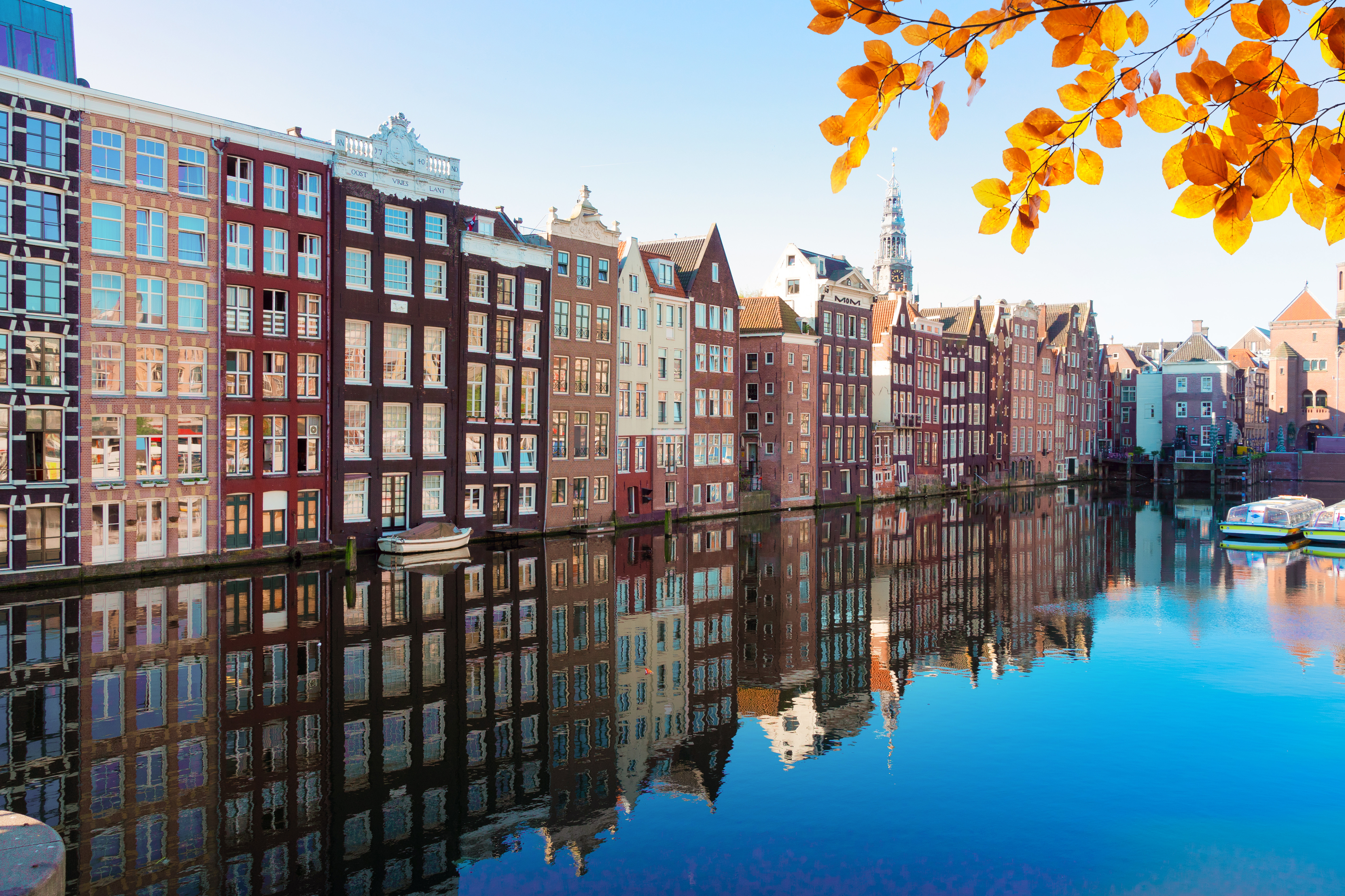 Kanaali ja syksyn lehdet Amsterdamissa, Hollannissa, heijastuvat värikkäisiin rakennuksiin rauhallisessa vedessä