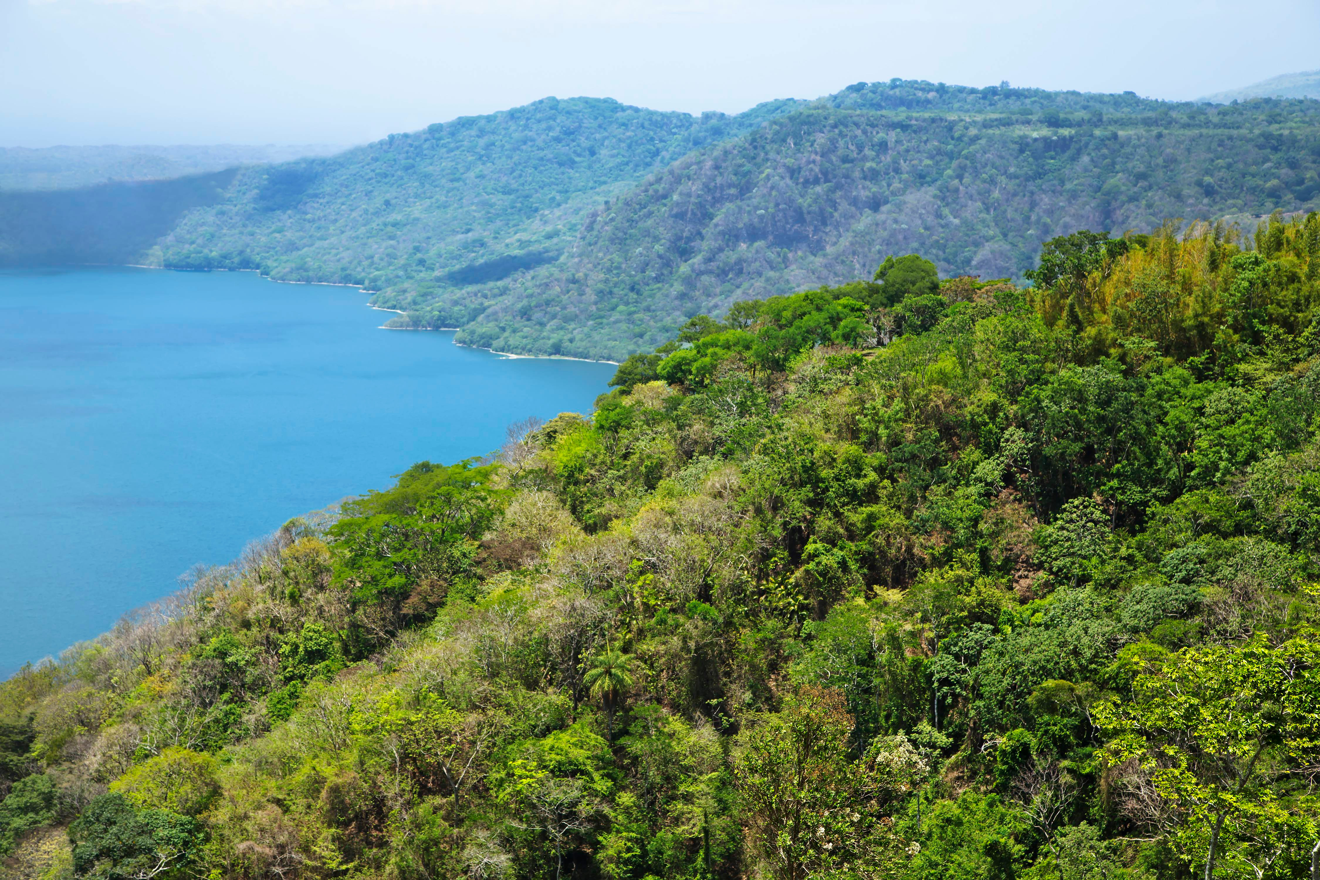 View of lush green forested hills overlooking a serene blue lake, capturing the natural beauty and tranquility of the landscape
