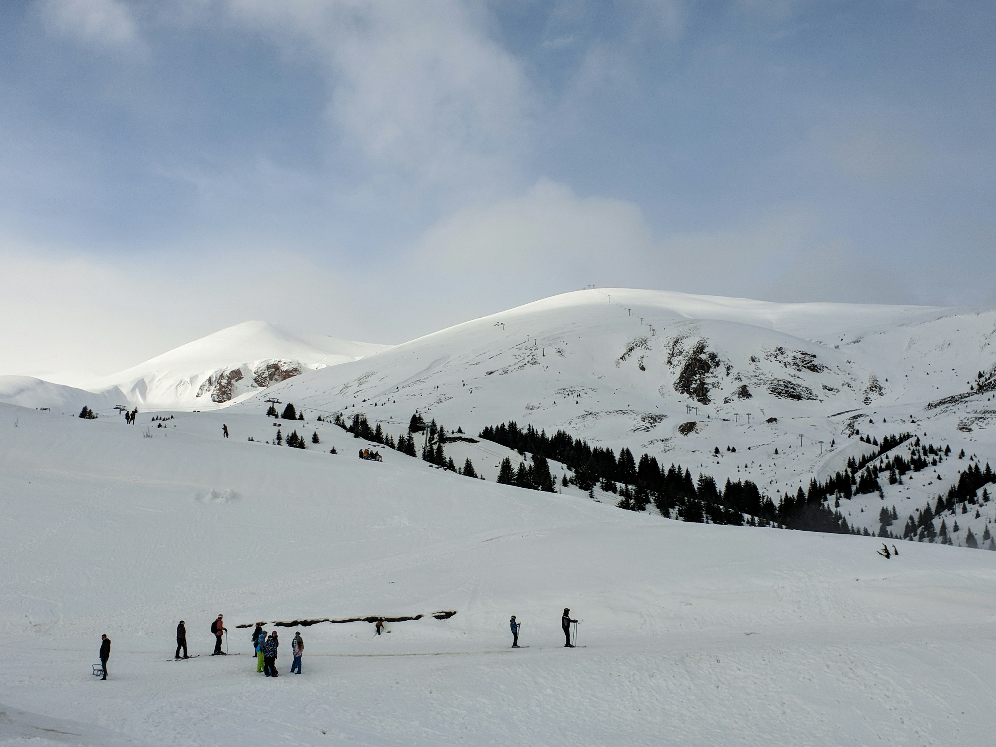 Travel to Popva Shapka - Snow-covered ski slopes and plains with mountains in the background meeting blue sky
