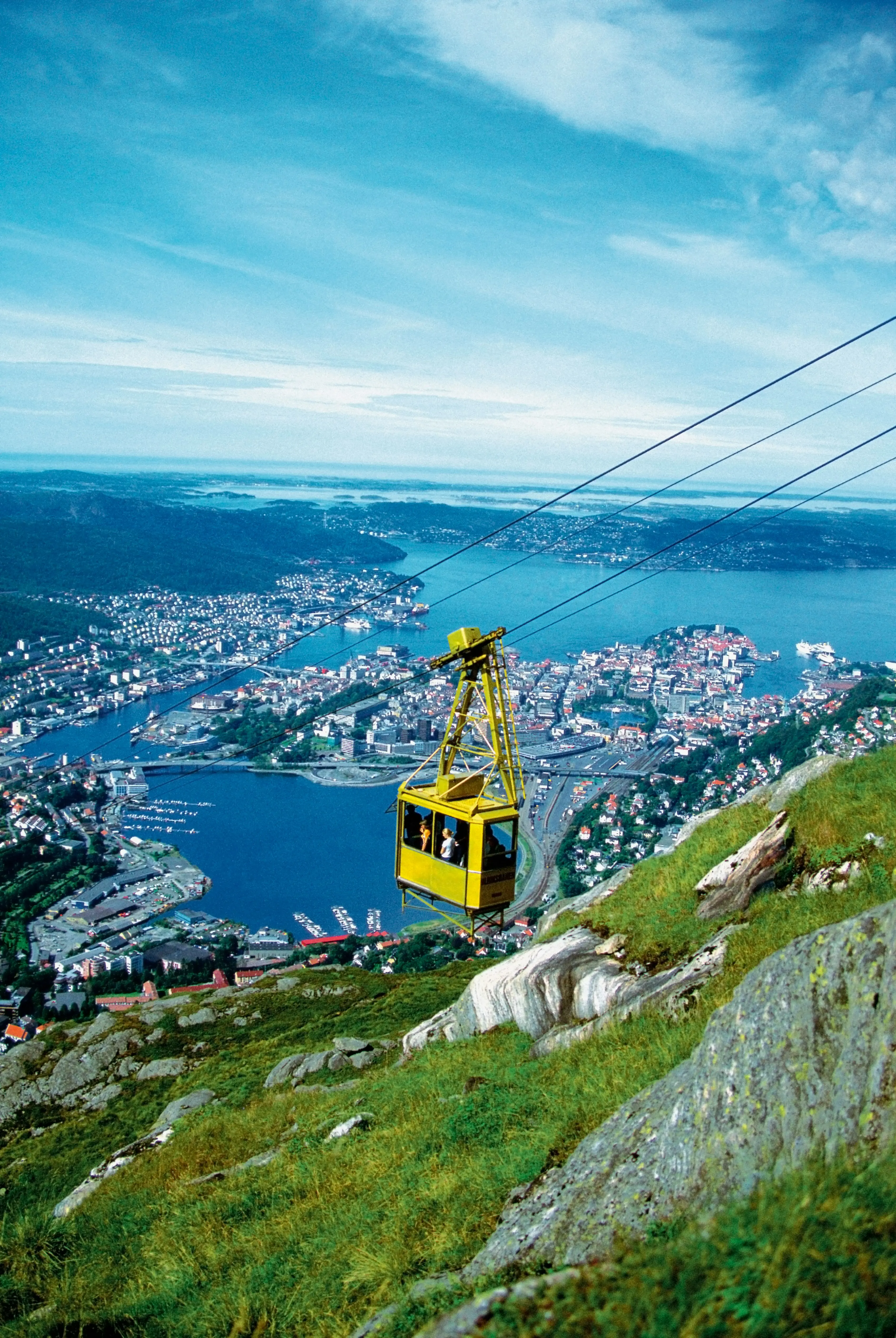 Gul linbana som stiger upp på Mount Fløyen med panoramautsikt över Bergen, Norge, inklusive stadsbild och hamn under en klarblå himmel
