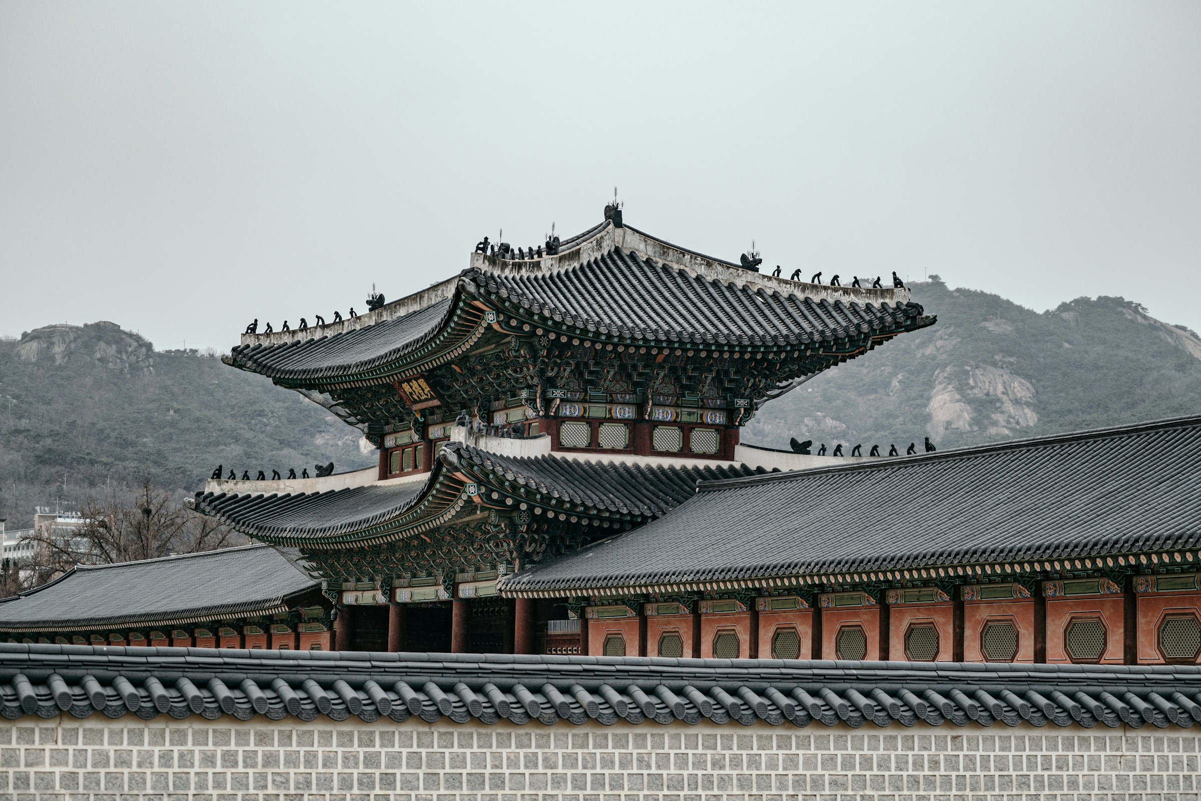 Historic Korean palace architecture with ornate roof design and mountain backdrop.