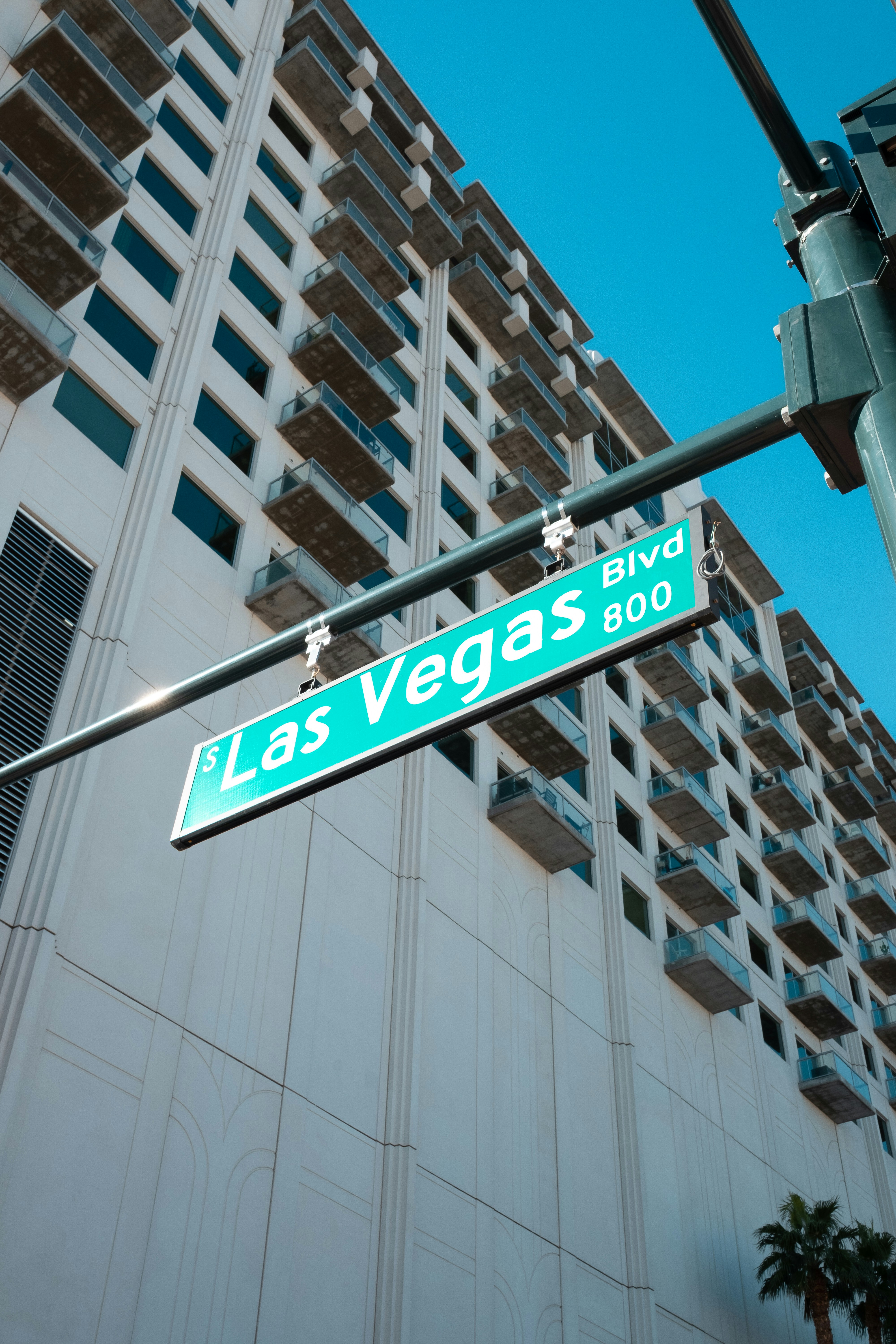 Street sign for Las Vegas Blvd with a high-rise building in the background against a clear blue sky