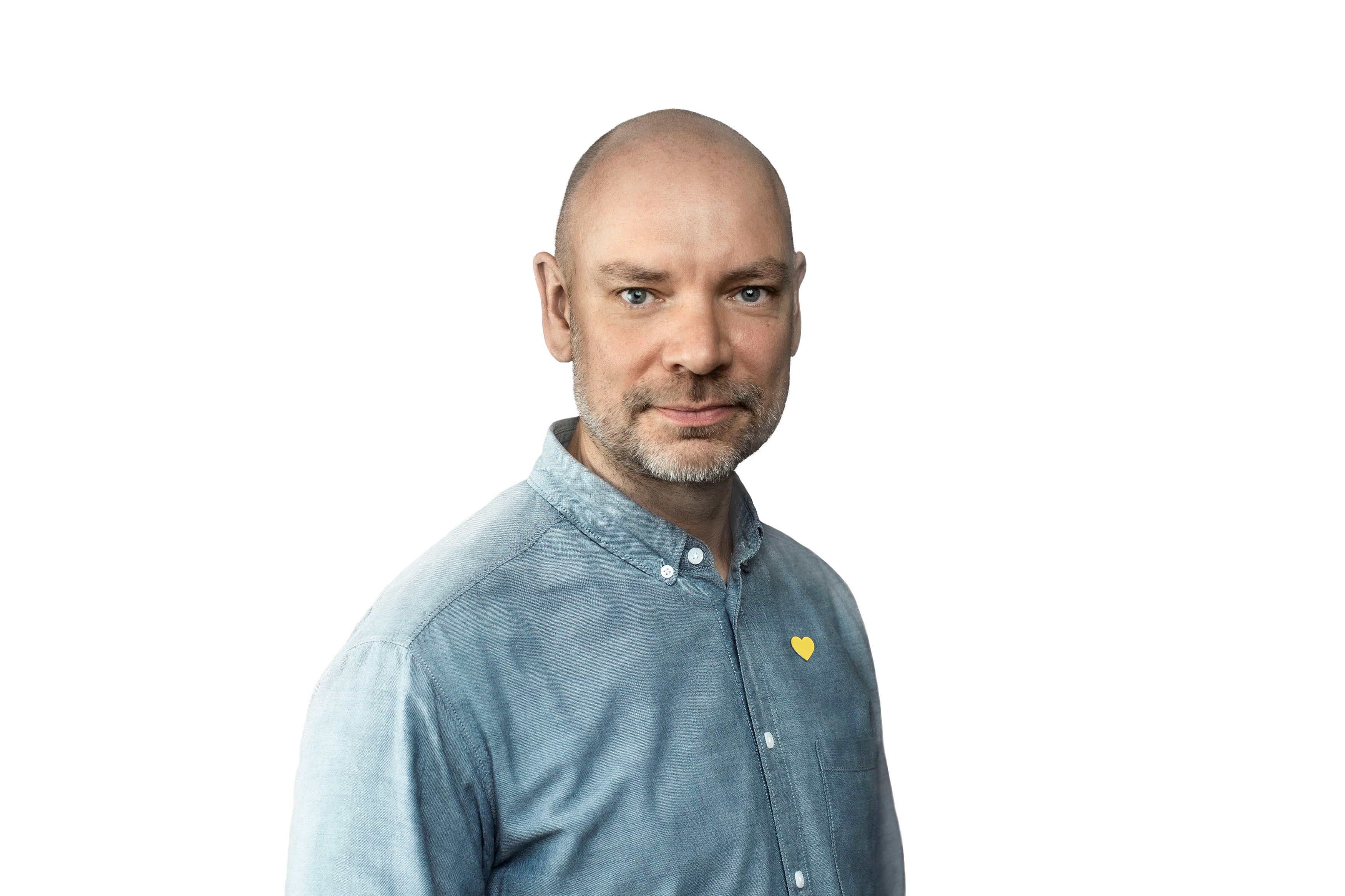 Person wearing a blue button-up shirt with a yellow heart pin, standing against a white background.